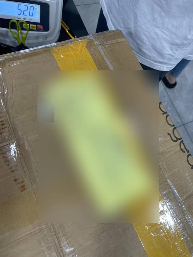 The sealed parcel on our scale, 5.2 kg, with a GDEX waybill on top (blurred)